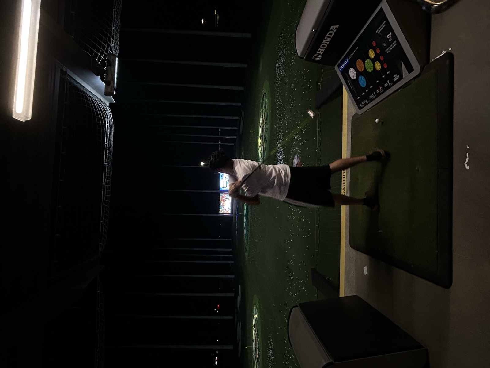 Fahmid swinging a golf club at a driving range at night