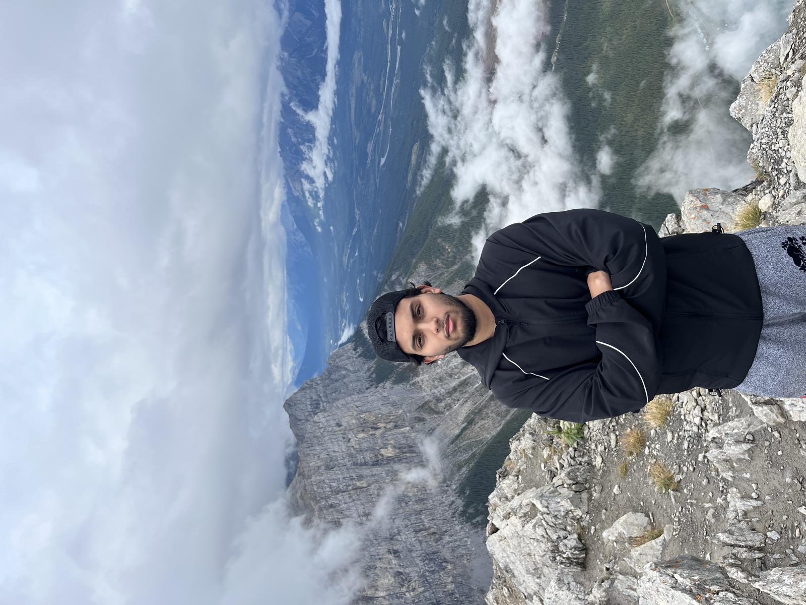 Fahmid on a rocky mountaintop above a cloud-filled valley