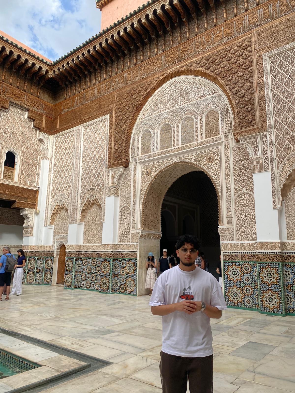 Fahmid standing in a courtyard with ornate carved arches